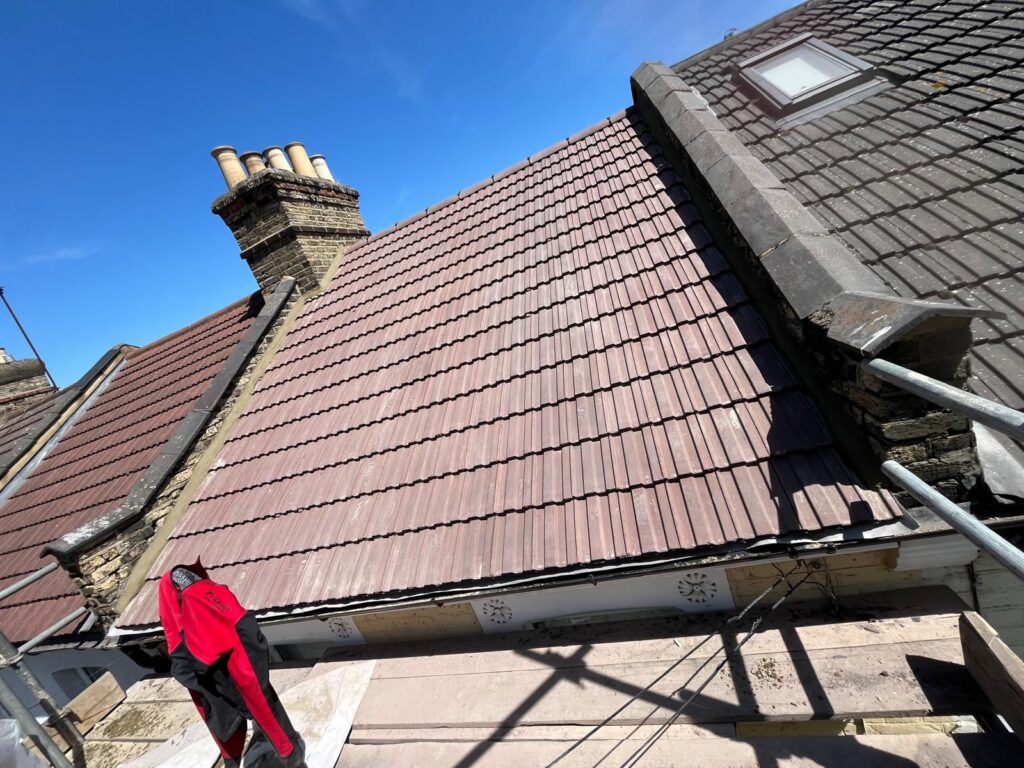 New Roof Installations 4 Roof replacement project by checka roof ltd, showing a blend of old and new tiles, chimney, and skylight during construction in london, essex, or kent.